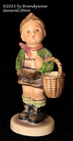 A small Hummel figurine titled Village Boy showing a young boy carrying a basket and is from trademark 6