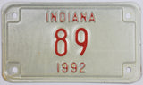 A NOS 1992 Indiana motorcycle license plate with a low DMV registration number. The 92 IN plate is in Excellent Minus condition.