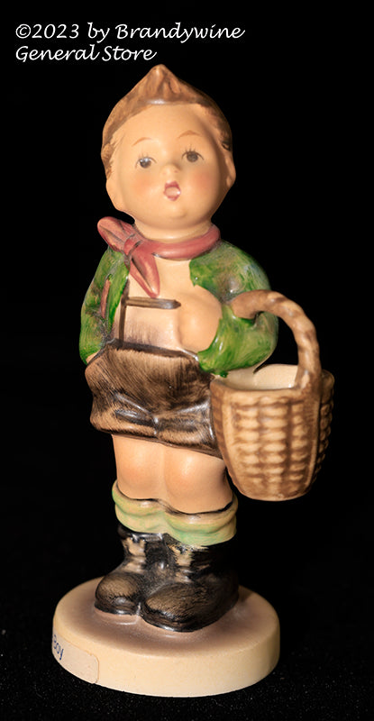 A small Hummel figurine titled Village Boy showing a young boy carrying a basket and is from trademark 6
