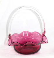 A larger size Pilgrims hand blown cranberry basket with clear applied handle